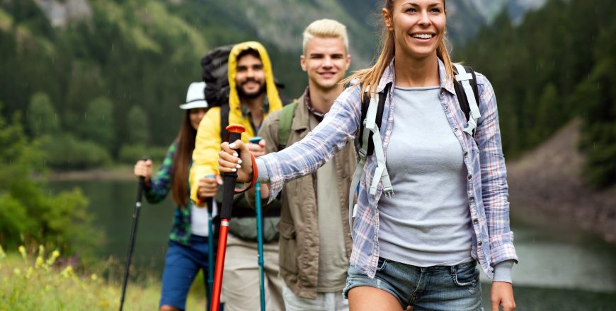 Group of smiling friends hiking with backpacks outdoors. Travel, tourism, hike and people concept.