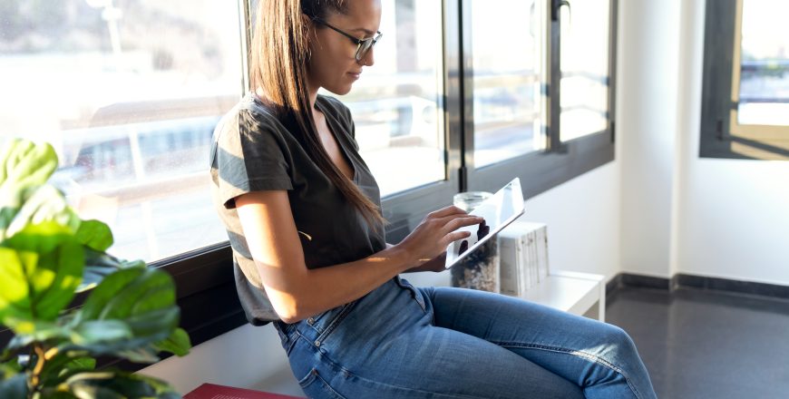 Pretty young business woman using her digital tablet while sitti