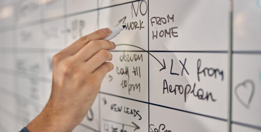 Young man writing on whiteboard at work